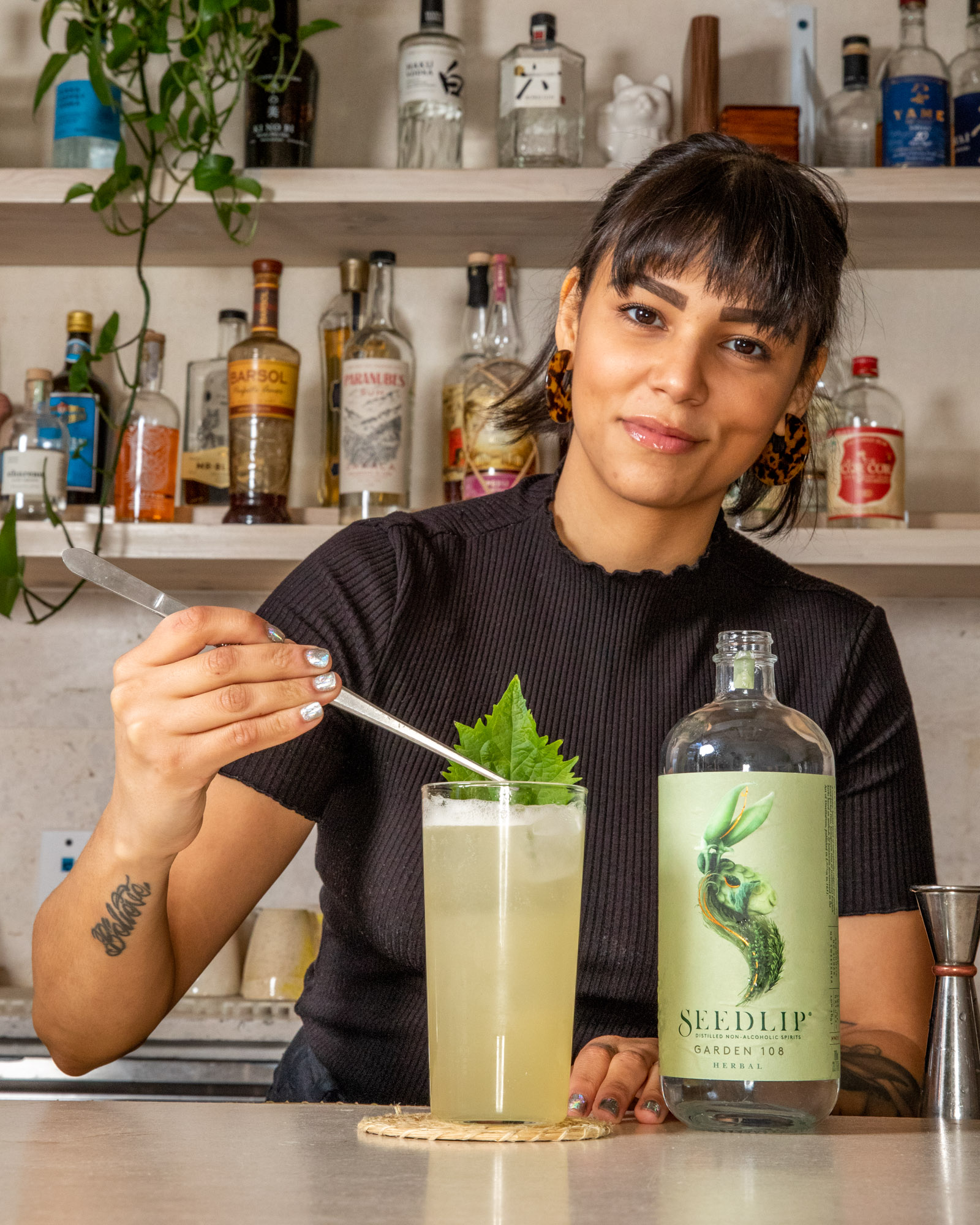 Bartender looking into the camera while she puts a garnish on a drink