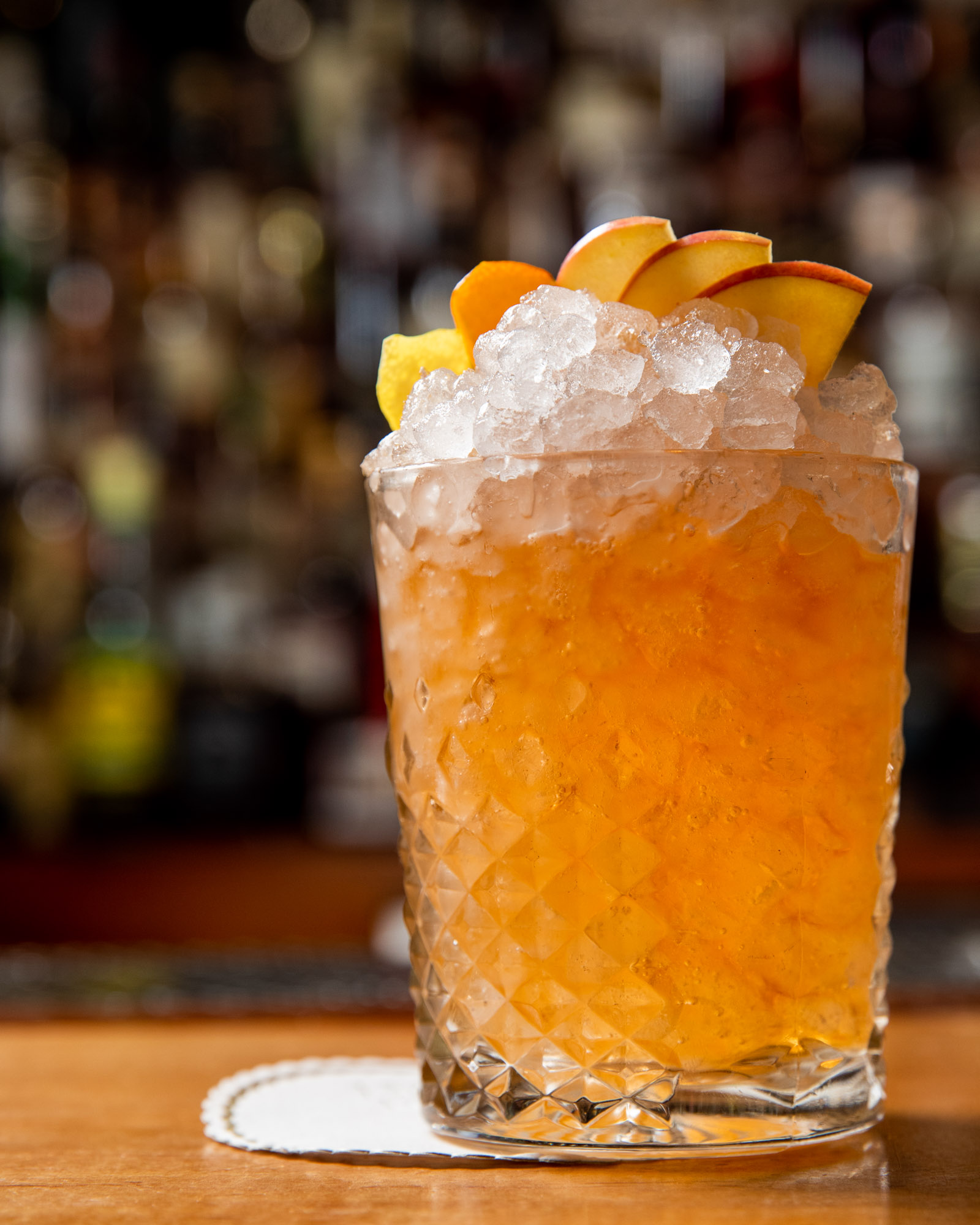 Tropical cocktail with a mound of ice and peach garnish