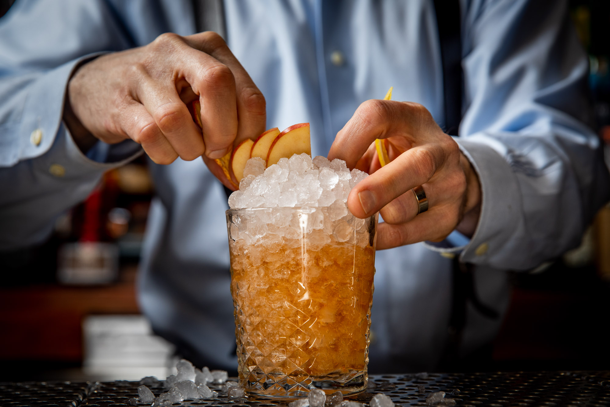 bartender putting a peach garnish on a drink