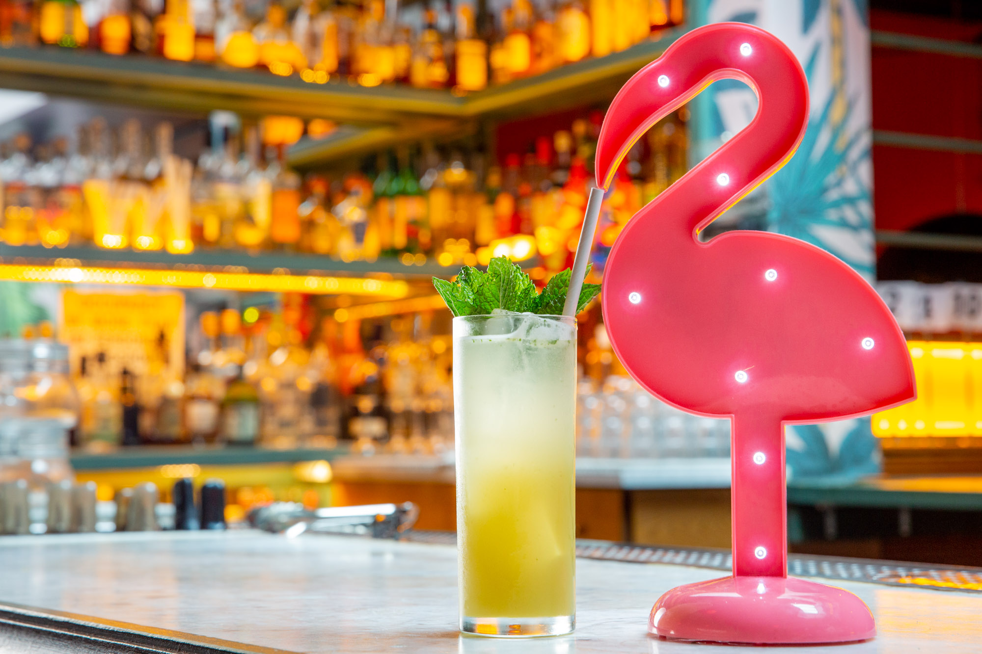 Flamingo taking a sip of a tropical cocktail