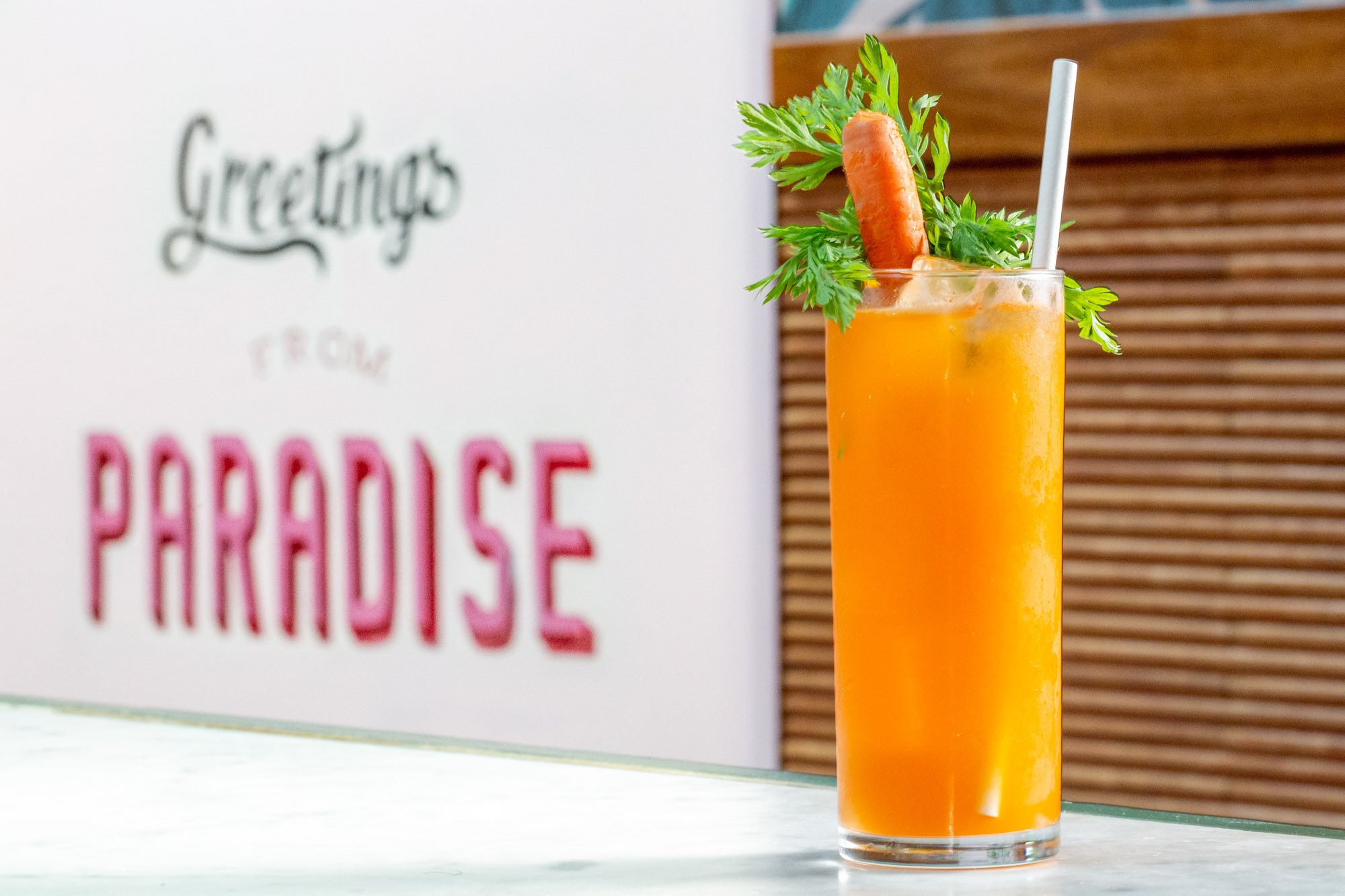 cocktail with a carrot placed next to a sign