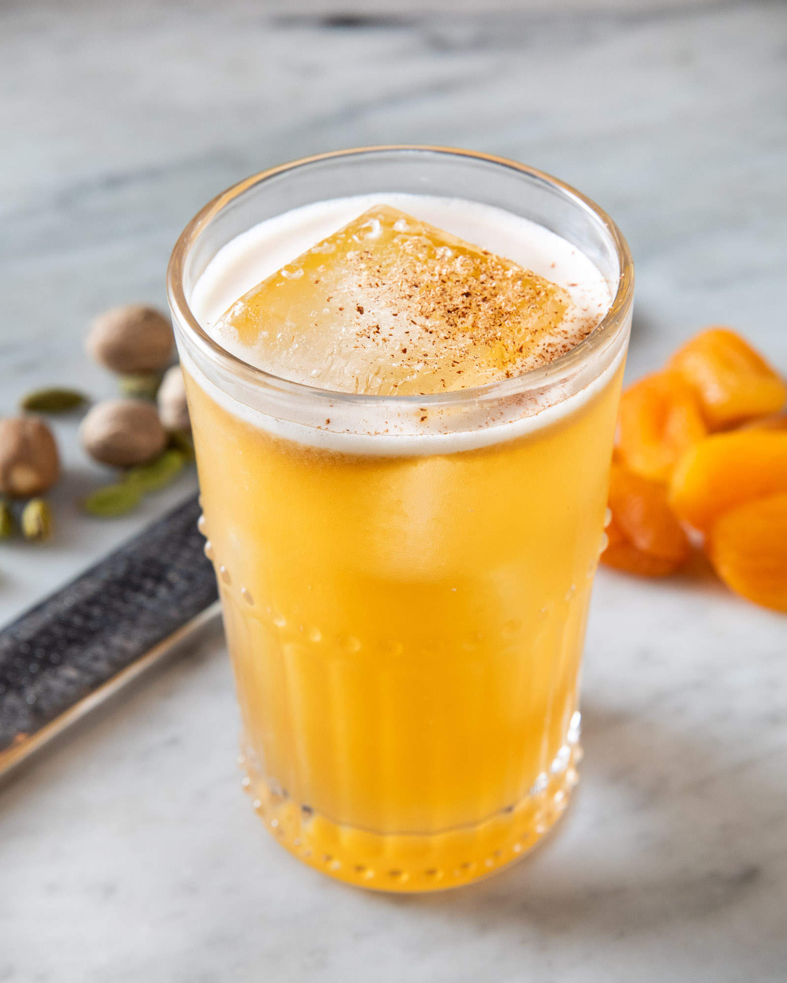 colorful orange cocktail with a nutmeg garnish