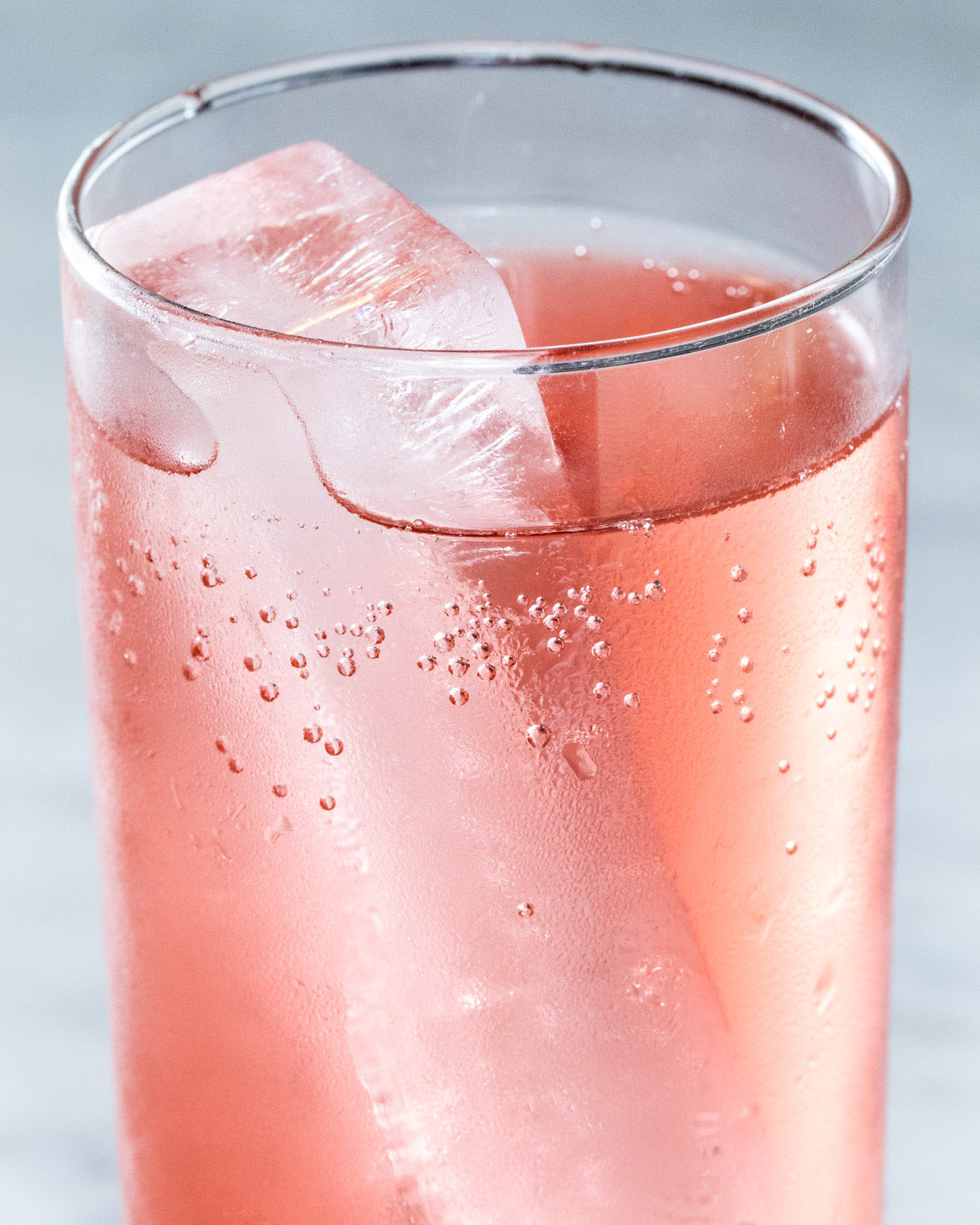 detail photograph of a drink with an icecube and carbonated bubbles